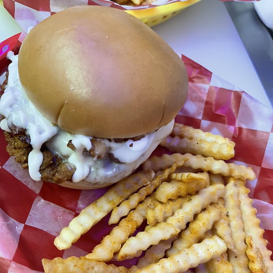 A Route 10 Drive-In fried chicken sandwich with white sauce and crinkle-cut fries.