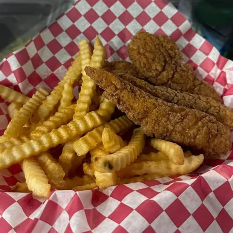 Crispy chicken tenders and crinkle-cut fries served in a red and white checkered paper basket.