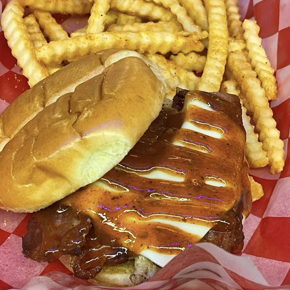 Route 10 Drive-In's BBQ sandwich with melted cheese and crinkle-cut fries in a red checkered basket.