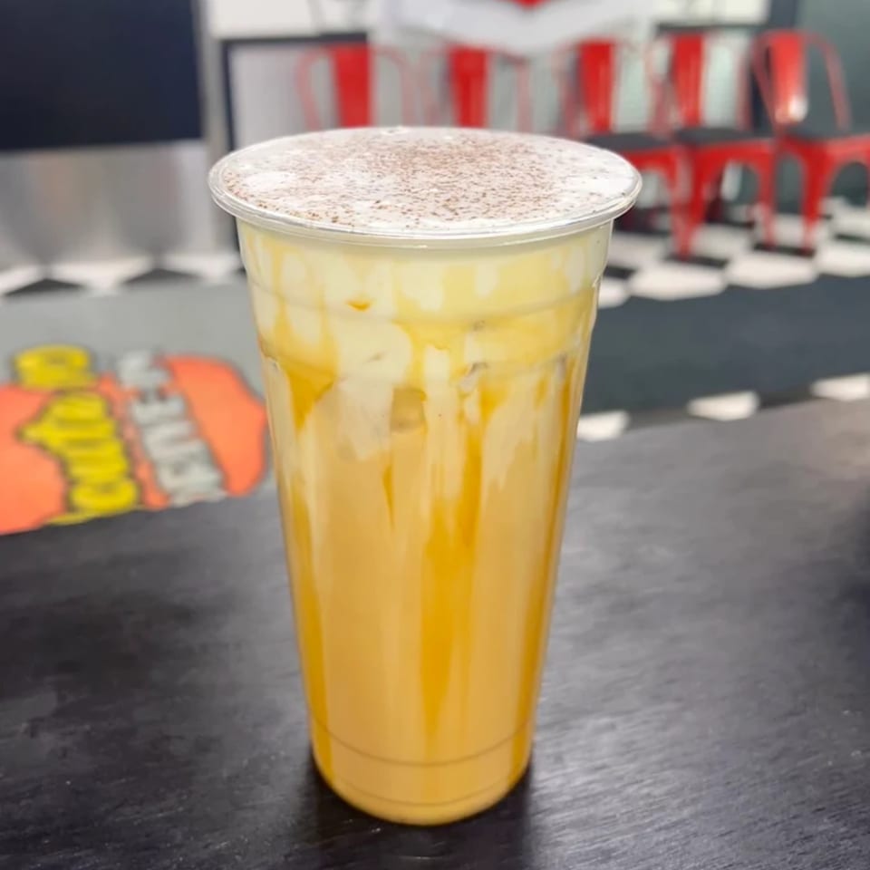 A Route 10 Drive-In fast-food drink with whipped cream and chocolate powder on a black table.